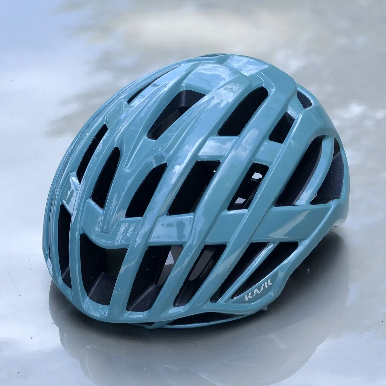 A blue KASK cycling helmet on a pale gray surface.