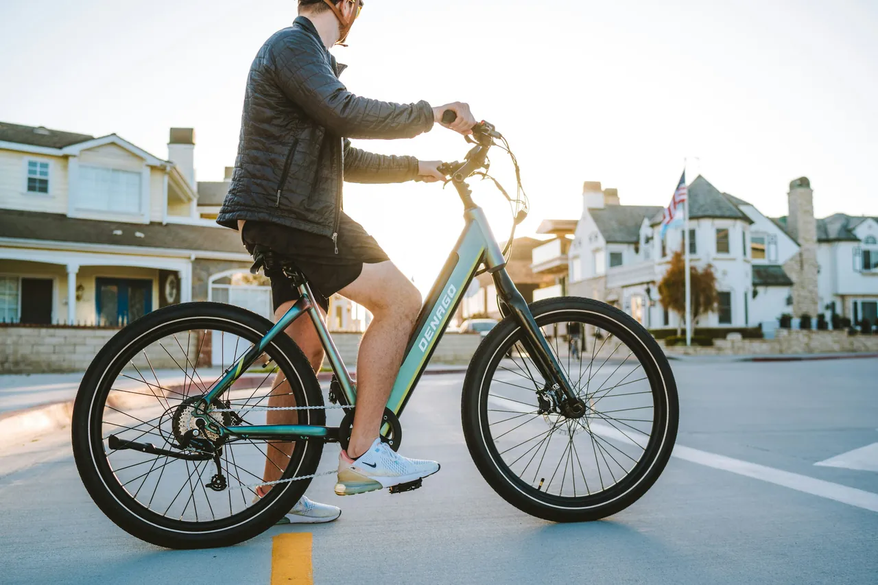 Rider on a step-through Denago electric bike in a residential street.