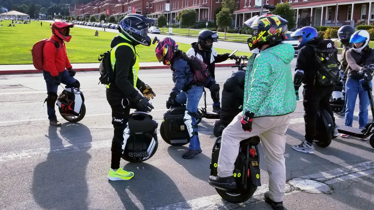 Electric unicycle riders wearing full-face helmets and protective gear pause together in San Francisco.