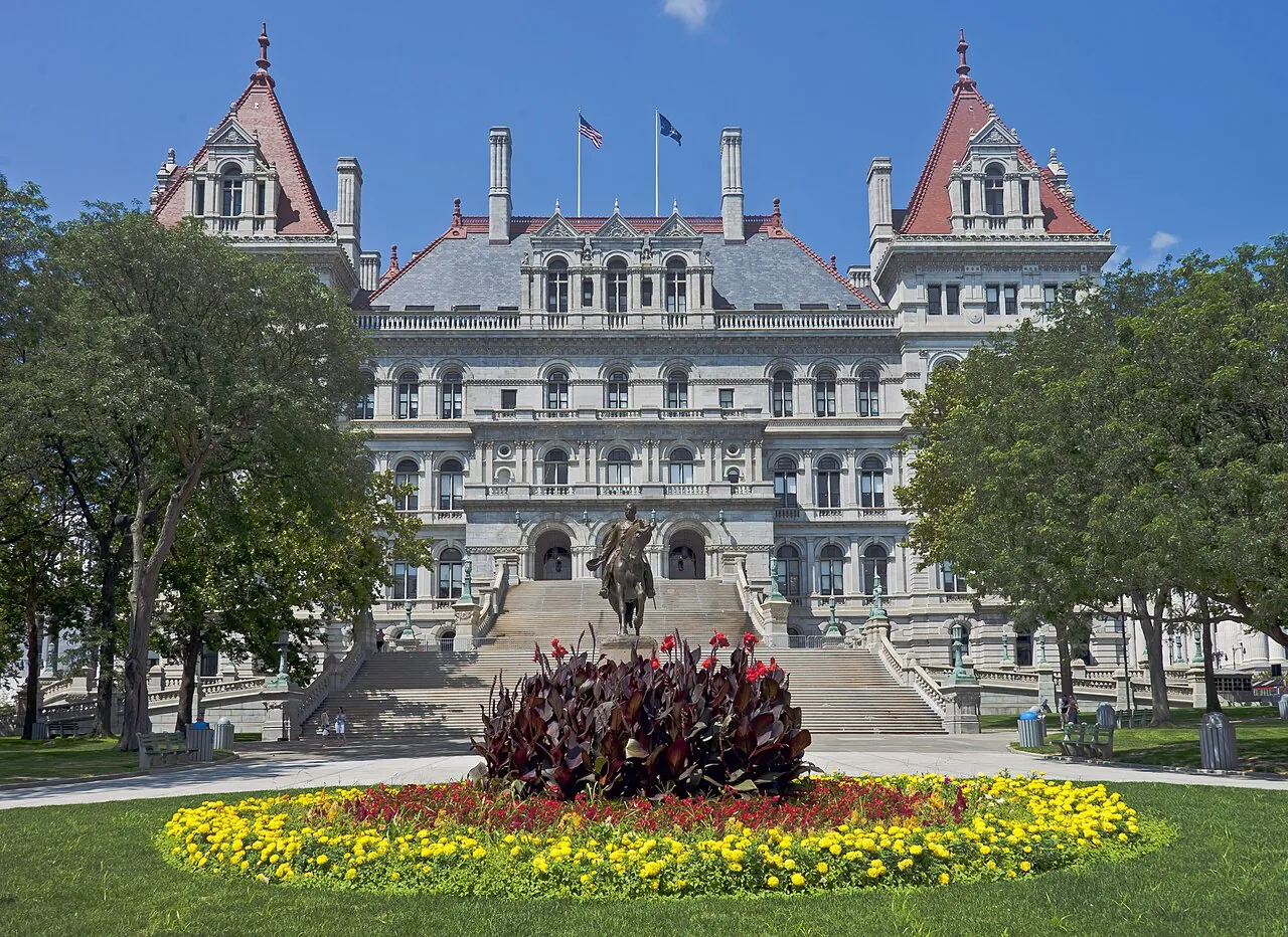 The east facade of the New York State Capitol, with a flower bed in the foreground.