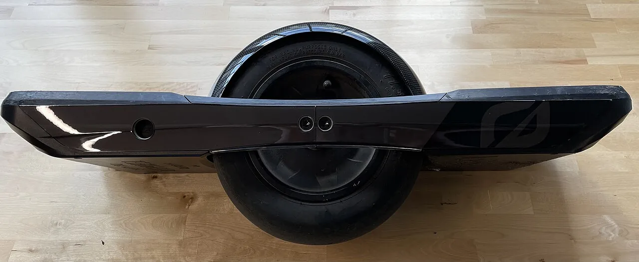 A black Onewheel GT with a fender and rail guards on a wood floor.